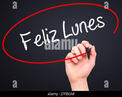 Man Hand writing Feliz Lunes (Happy Monday In Spanish) with black marker on visual screen. Isolated on black. Business, technology, internet concept.  Stock Photo