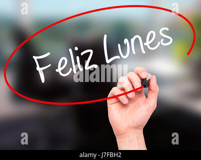 Man Hand writing Feliz Lunes (Happy Monday In Spanish) with black marker on visual screen. Isolated on office. Business, technology, internet concept. Stock Photo