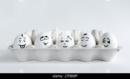 Eggs with funny faces in the package on a white background. Easter Concept Photo. Eggs. Faces on the eggs Stock Photo