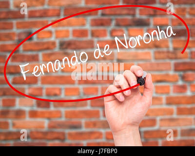 Man Hand writing Fernando de Noronha with black marker on visual screen. Isolated on bricks. Business, technology, internet concept. Stock Photo Stock Photo