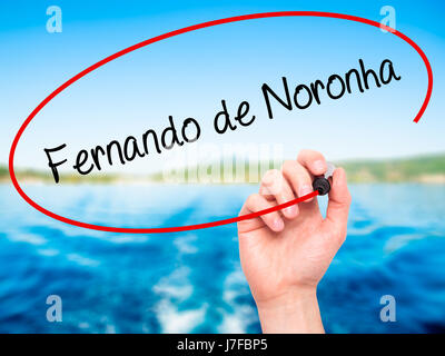 Man Hand writing Fernando de Noronha with black marker on visual screen. Isolated on nature. Business, technology, internet concept. Stock Photo Stock Photo