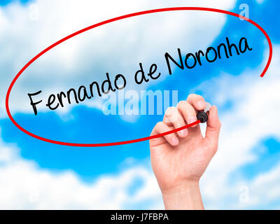 Man Hand writing Fernando de Noronha with black marker on visual screen. Isolated on sky. Business, technology, internet concept. Stock Photo Stock Photo
