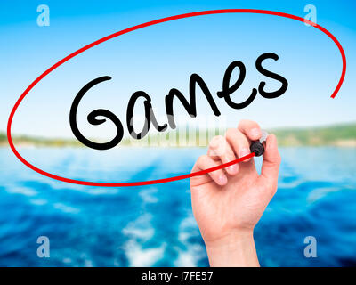Man Hand writing Games with black marker on visual screen. Isolated on background. Business, technology, internet concept. Stock Photo Stock Photo