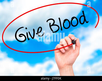 Man Hand writing Give Blood  with black marker on visual screen. Isolated on sky. Business, technology, internet concept. Stock Photo