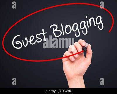 Man Hand writing Guest Blogging  with black marker on visual screen. Isolated on black. Business, technology, internet concept. Stock Photo Stock Photo