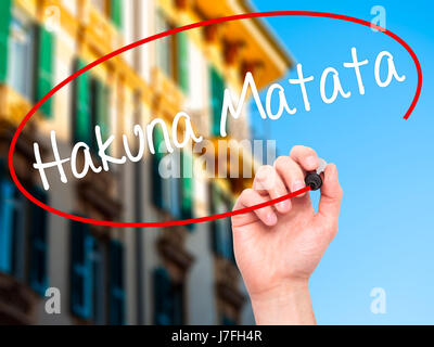 Man Hand writing Hakuna Matata (Swahili phrase; it means &quot;no worries&quot;) with black marker on visual screen. Isolated on city. Business, techn Stock Photo
