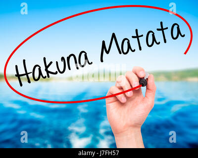 Man Hand writing Hakuna Matata (Swahili phrase; it means &quot;no worries&quot;) with black marker on visual screen. Isolated on nature. Business, tec Stock Photo