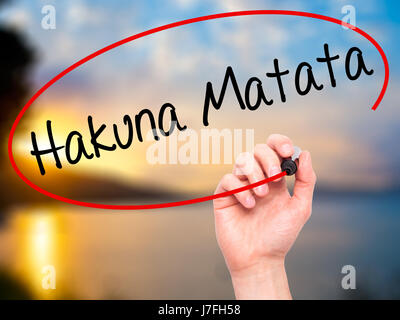 Man Hand writing Hakuna Matata (Swahili phrase; it means &quot;no worries&quot;) with black marker on visual screen. Isolated on nature. Business, tec Stock Photo