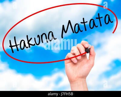 Man Hand writing Hakuna Matata (Swahili phrase; it means &quot;no worries&quot;) with black marker on visual screen. Isolated on sky. Business, techno Stock Photo