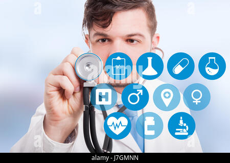 Male doctor with stethoscope and virtual screen with different healthcare buttons Stock Photo