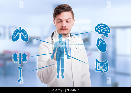 Handsome medic pressing modern medical interface with human body anatomy Stock Photo