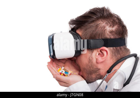 Male doctor wearing vr glasses and eating many pills on white background as drug addiction concept Stock Photo