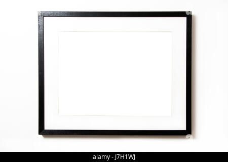 Black rectangular frame with mat, blank inside, hanging on a white wall Stock Photo