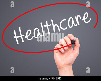 Man Hand writing Healthcare with black marker on visual screen. Isolated on grey. Business, technology, internet concept. Stock Photo Stock Photo