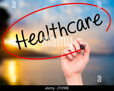 Man Hand writing Healthcare with black marker on visual screen. Isolated on nature. Business, technology, internet concept. Stock Photo Stock Photo