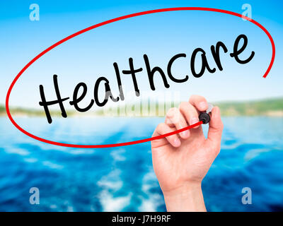 Man Hand writing Healthcare with black marker on visual screen. Isolated on nature. Business, technology, internet concept. Stock Photo Stock Photo