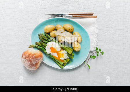 Light spring lunch on the plate. Fried asparagus, fresh potatoes and poached egg with parmesan cheese. healthy food. Stock Photo