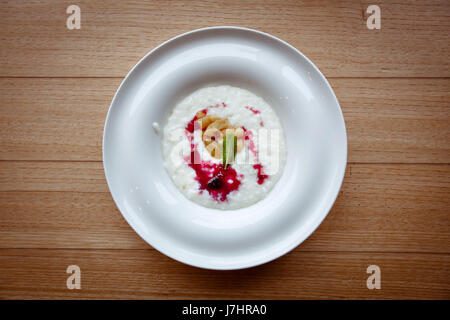 Rice porridge in plate with berries wooden table Stock Photo