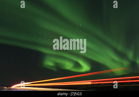 A truck passes by on the Richardson Highway in Alaska as the Northern Lights or Aurora Borealis light up the sky. Stock Photo