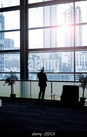 Businessman looking true windows from building resting room Stock Photo