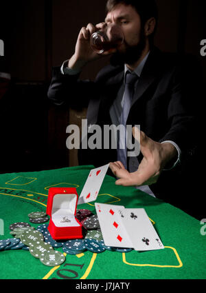 Poker player showing a losing combination in a poker cards, man drinks whiskey from grief. Stock Photo