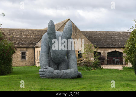 'Lady Hare' by Sophie Ryder crouched on lawn in front of converted cottage