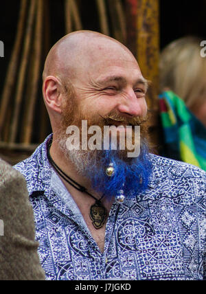 Bald, blue bearded man laughs with friends at Castle Carrock, Cumbria. Stock Photo