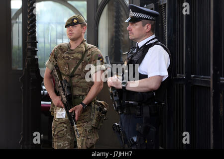 Members of the army join police officers outside the Palace of Westminster, London, after Scotland Yard announced armed troops will be deployed to guard 'key locations' such as Buckingham Palace, Downing Street, the Palace of Westminster and embassies. Stock Photo