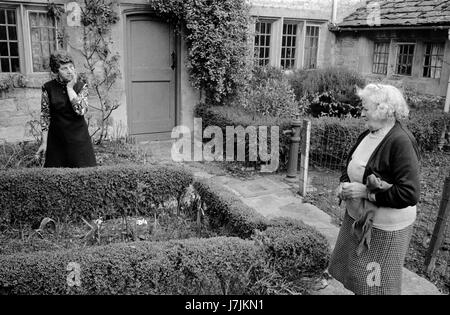Neighbours two women chatting in the street 1970s Britain UK. Village life 1975 The Cotswolds. Lower and Upper Slaughter are twin villages on the River Eye and are know as The Slaughters, Gloucestershire  HOMER SYKES Stock Photo