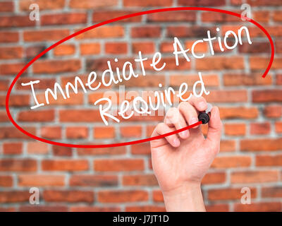 Man Hand writing Immediate Action Required with black marker on visual screen. Isolated on bricks. Business, technology, internet concept. Stock Photo Stock Photo