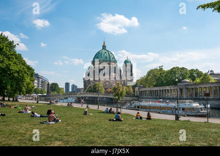 Berlin, Germany - may 23, 2017:People relaxing on meadow in Monbijoupark on a sunny day in Berlin with the Berlin cathedral and tourist boat in backgr Stock Photo