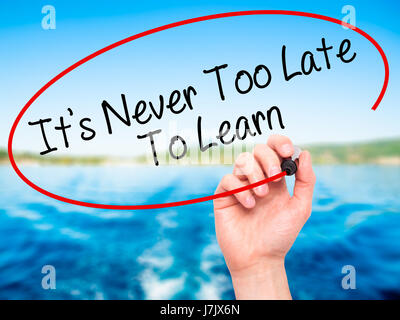 Man Hand writing Its Never Too Late To Learn with black marker on visual screen. Isolated on background. Business, technology, internet concept. Stock Stock Photo