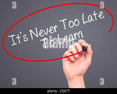 Man Hand writing Its Never Too Late To Learn with black marker on visual screen. Isolated on background. Business, technology, internet concept. Stock Stock Photo