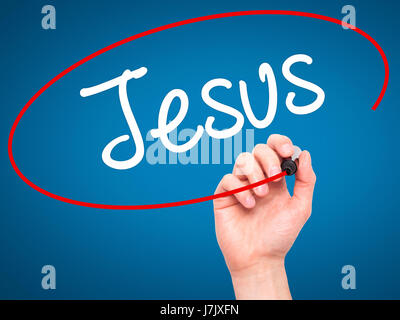 Man Hand writing Jesus  with black marker on visual screen. Isolated on blue. Business, technology, internet concept. Stock Photo Stock Photo