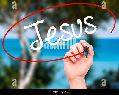 Man Hand writing Jesus  with black marker on visual screen. Isolated on nature. Business, technology, internet concept. Stock Photo Stock Photo