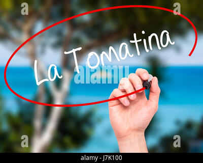 Man Hand writing La Tomatina with black marker on visual screen. Isolated on nature. Business, technology, internet concept. Stock Photo