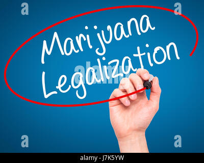 Man Hand writing Marijuana Legalization with black marker on visual screen. Isolated on blue. Live, technology, internet concept. Stock Photo Stock Photo