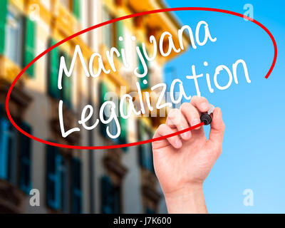 Man Hand writing Marijuana Legalization with black marker on visual screen. Isolated on city. Live, technology, internet concept. Stock Photo Stock Photo