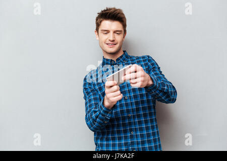 Young concentrated man wearing casual playing games on smartphone Stock Photo