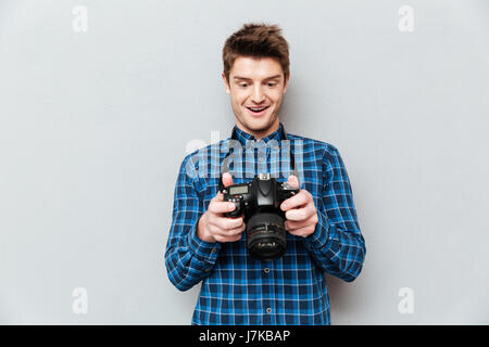 Young funny man looking at images on camera and surprising isolated Stock Photo