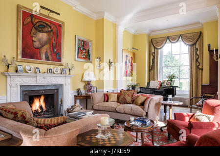 Mixed modern art and antique furniture in large yellow drawing room. The curtain fabric is Agrippina Gold by Marvic Textiles Stock Photo