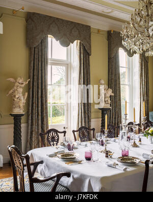 Georgian style dining chairs in grand dining room with glass chandelier marble busts on plinths Stock Photo