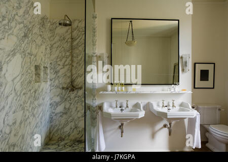 Marble shower unit with large mirror above double basins in Portland Road, London, UK Stock Photo