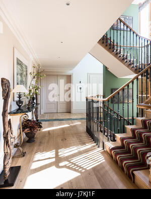 Marble-topped console table in hallway with painting by Scottish artist Joyce Cairns. The staircase runner is by Tim Page Stock Photo