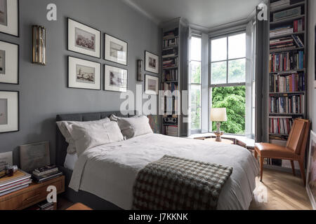 Calm grey tones and book shelving in bedroom with 1940s Murano glass wall lights Stock Photo