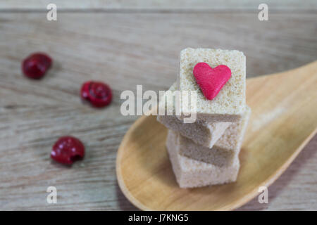 Brown sugar cubes in wooden spoon on wood background Stock Photo