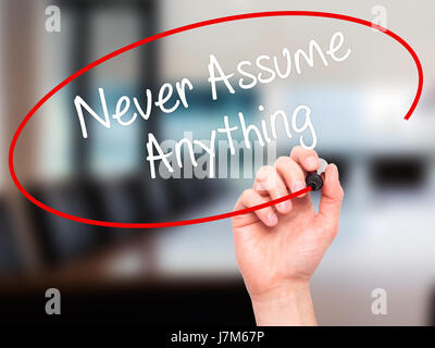 Man Hand writing Never Assume Anything with black marker on visual screen. Isolated on office. Business, technology, internet concept. Stock Photo Stock Photo