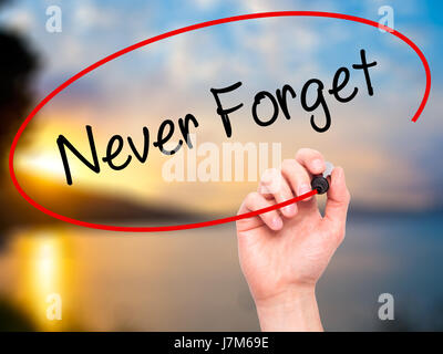 Man Hand writing Never Forget  with black marker on visual screen. Isolated on nature. Business, technology, internet concept. Stock Photo Stock Photo