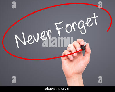 Man Hand writing Never Forget  with black marker on visual screen. Isolated on grey. Business, technology, internet concept. Stock Photo Stock Photo