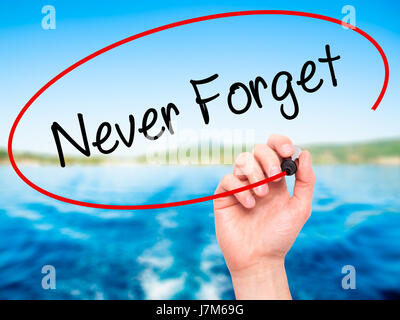 Man Hand writing Never Forget  with black marker on visual screen. Isolated on nature. Business, technology, internet concept. Stock Photo Stock Photo